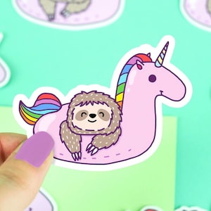 May include: A pink unicorn pool float with a rainbow mane and tail. A brown sloth with a happy expression is relaxing on the float.