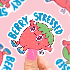 Pode incluir: Um adesivo com um morango de desenho animado com uma cara triste e o texto "Berry Stressed". O morango est&aacute; usando t&ecirc;nis e tem uma folha verde no topo.