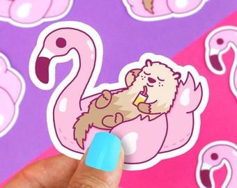 May include: A pink flamingo pool float with a brown and white otter relaxing inside. The otter is holding a yellow drink and has a relaxed expression.
