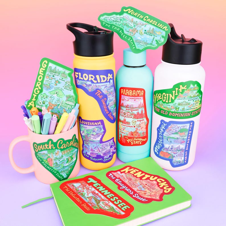 Puede incluir: Surtido de pegatinas de colores en forma de estado que presentan los contornos de cada estado y varios puntos de referencia. Las pegatinas se colocan en una variedad de art&iacute;culos, que incluyen una taza, botellas de agua y un cuaderno.