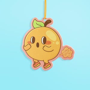 May include: A cartoon-style air freshener in the shape of a yellow fruit character with a surprised expression. The character has small orange shoes and is emitting a cloud of brown gas. It is hanging from a yellow string.