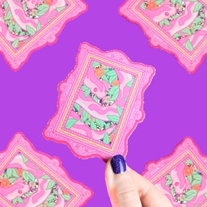 May include: Pink framed sticker with a glittery pink and green design of a rabbit in a floral pattern.