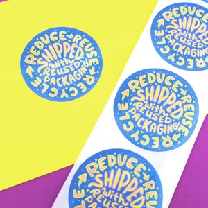 May include: A roll of blue and pink circular stickers with the text "REDUCE REUSE RECYCLE SHIPPED WITH REUSED PACKAGING" in a circular pattern.