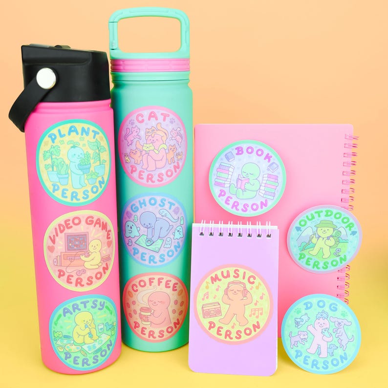 Puede incluir: Una colecci&oacute;n de pegatinas y botellas de agua coloridas con ilustraciones caprichosas. Las pegatinas presentan varios dise&ntilde;os de "Persona", incluyendo "Persona Planta", "Persona Videojuegos" y "Persona Art&iacute;stica". Las botellas son rosas y turquesas.