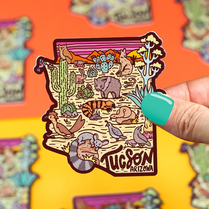 May include: A colorful illustration of the state of Arizona with the word "Tucson" and "Arizona" written below. The illustration features a variety of desert animals, plants, and cacti.