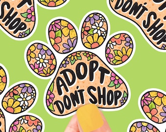 May include: A paw print sticker with a floral design and the text "Adopt Don't Shop".
