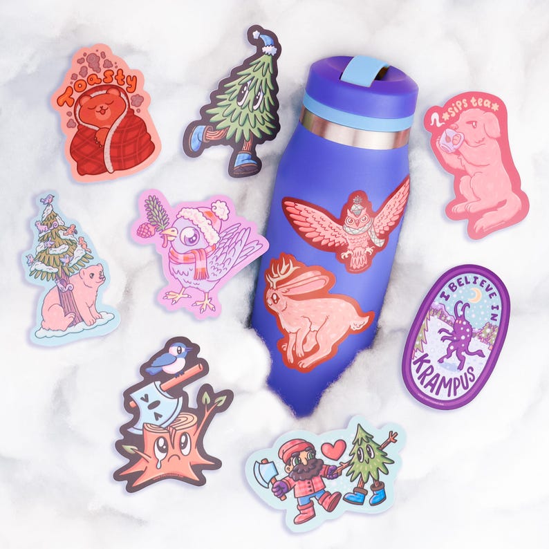 Puede incluir: Una colecci&oacute;n de pegatinas coloridas con ilustraciones caprichosas, que incluyen un oso envuelto en una manta, un &aacute;rbol con una cara y un perro rosa bebiendo t&eacute;. Una botella de agua azul est&aacute; decorada con pegatinas de un b&uacute;ho y un conejo.