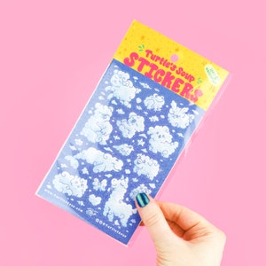 May include: A sheet of stickers featuring cute cloud illustrations with various animal faces. The stickers are packaged in a clear plastic bag with a pink and blue header that reads "Turtle's Soup Stickers".