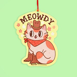 May include: A yellow and orange cat wearing a cowboy hat and bandana with the text "MEOWDY" on a yellow background with white flowers.
