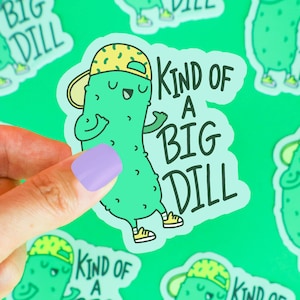 Pu&ograve; includere: Un cetriolo di cartone animato verde con un berretto da baseball giallo e verde e il testo "Kind of a Big Dill".