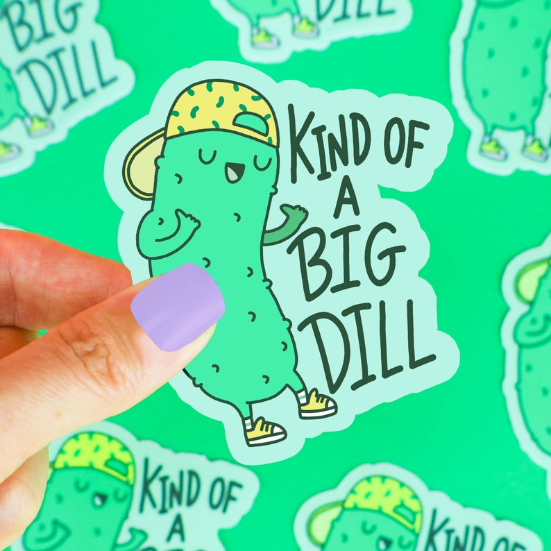 Pu&ograve; includere: Un cetriolo di cartone animato verde con un berretto da baseball giallo e verde e il testo "Kind of a Big Dill".