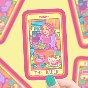 May include: A pink and blue illustrated sticker of a woman baking cookies and a cake. The sticker is in the shape of a smartphone screen and says "THE BAKER" at the bottom.
