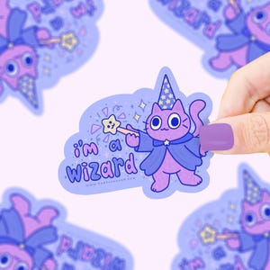 May include: A sticker featuring a purple cat dressed as a wizard, holding a star-shaped wand. The sticker has the text "I'm a Wizard" and is surrounded by stars and sparkles. The cat wears a blue cape and wizard hat.