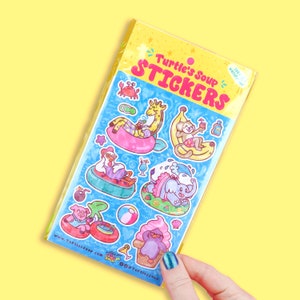 May include: A sheet of colorful stickers featuring various animals enjoying summer activities. The stickers are from Turtle's Soup and feature a giraffe, monkey, chicken, elephant, and penguin. The stickers are perfect for adding a touch of whimsy to your planner, laptop, or water bottle.