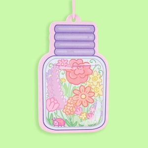 May include: A pink glass jar with a purple lid filled with colorful flowers and a small pink bug. The jar is hanging from a string.