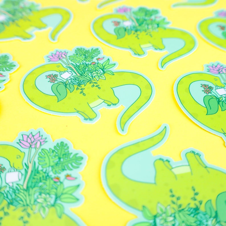 May include: A set of green dinosaur stickers with a light blue outline. Each dinosaur is carrying a variety of plants and flowers in a pot. The stickers are on a yellow background.