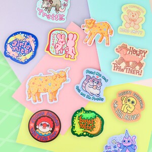Puede incluir: Una colecci&oacute;n de pegatinas coloridas con varios personajes de dibujos animados y frases. Los dise&ntilde;os incluyen una zarig&uuml;eya, conejitos, un perro, un gato, un payaso y un gato mago. Frases: "Tell me I'm Pretty", "Girl's Nite" y "I'm Still Alive!"