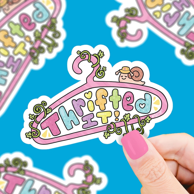 Peut inclure: Un autocollant rose et blanc avec un cintre et le texte "Thrifted It!" en couleurs arc-en-ciel. Un petit escargot avec un chapeau est sur le cintre. L'autocollant a une bordure blanche et un motif de vigne verte.