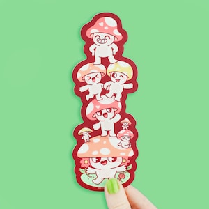 May include: A stack of five red and pink mushroom stickers with smiling faces. The mushrooms are stacked on top of each other, with the largest mushroom at the bottom and the smallest mushroom at the top. The mushrooms have white spots and are outlined in black.