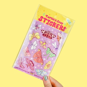 May include: A sheet of stickers featuring colorful illustrations of moths and butterflies on a purple background with white stars. The sheet is labeled "Turtle's Soup Stickers" with a small logo that says "Happy Little Critter".