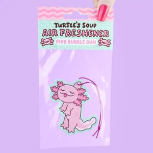 May include: Pink bubble gum scented air freshener in a clear plastic package. The air freshener features a cartoon axolotl design. The packaging reads "Turtle's Soup Air Freshener Pink Bubble Gum."