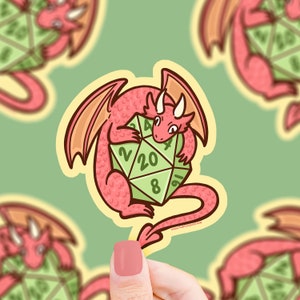 May include: A pink cartoon dragon holding a green twenty-sided die with numbers 2, 4, 8, 16, 20, and 4 printed on it. The dragon has a red nose and yellow eyes. The die is green with white numbers. The background is a light green color.