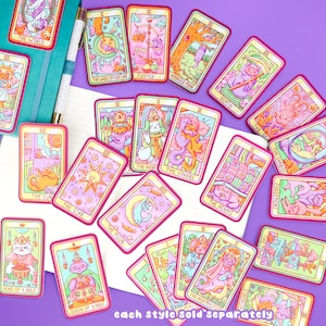 May include: A set of colorful tarot cards featuring cats in various poses. Each card has a red border and a yellow background with a pink and blue design. The cards are labeled with the names of the tarot cards, such as "The World", "The Wheel of Fortune", and "Justice".