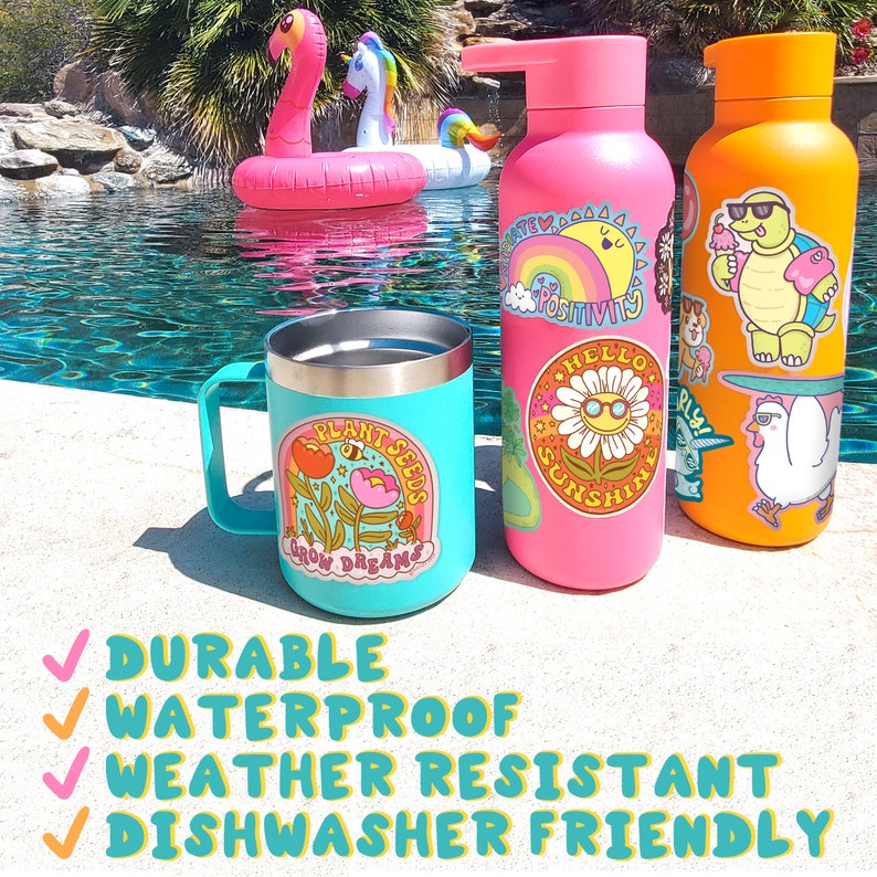 May include: Three colorful reusable water bottles with various stickers. The bottles are pink, orange, and turquoise. The stickers feature a variety of designs, including a sunflower, a turtle, and a rainbow. The bottles are sitting on a concrete surface near a swimming pool.