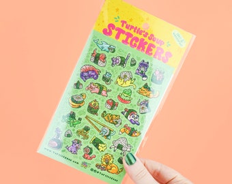 May include: A sheet of stickers featuring a variety of cute sushi rolls with different animals inside. The stickers are on a green background with the text "Turtle's Soup Stickers" in pink and yellow letters. The text "www.turtlesoup.com" and "@turtlesoup" are also included.