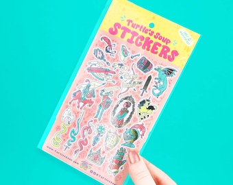 May include: A sheet of colorful stickers featuring various fantasy-themed illustrations, including knights, dragons, and swords. The stickers are packaged in a clear plastic sleeve with the text "Turtle's Soup Stickers" in pink and yellow. The stickers are waterproof.