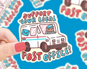 May include: A sticker with a cartoon illustration of a mail truck with a bear driver. The sticker says "Support Your Local Post Office!" in red and blue lettering.