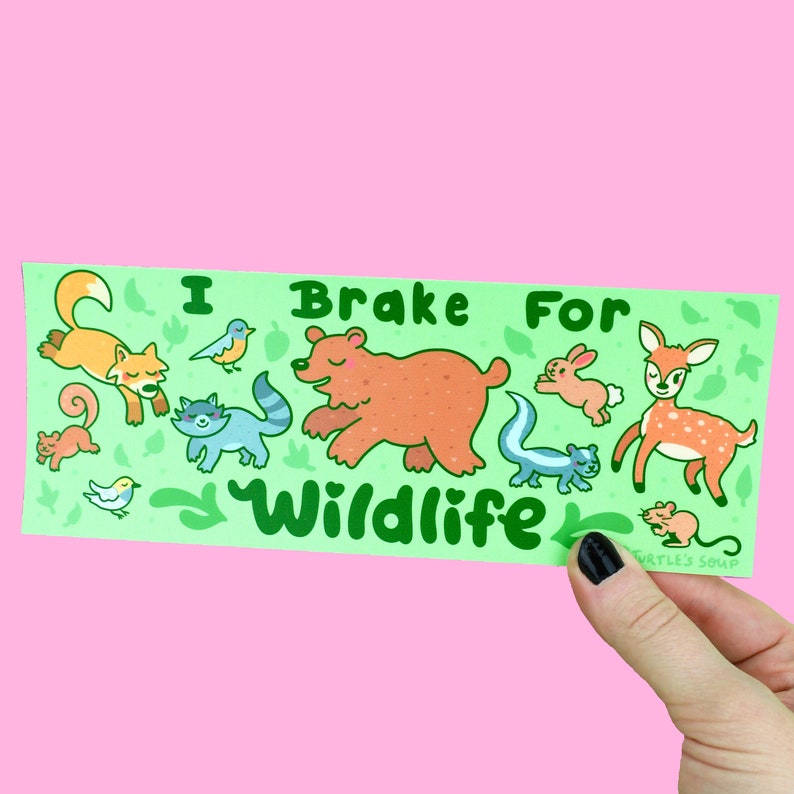May include: Green sticker with the text "I Brake For Wildlife" in green letters. The sticker features a cartoon illustration of a bear, deer, fox, raccoon, skunk, squirrel, rabbit, and birds.
