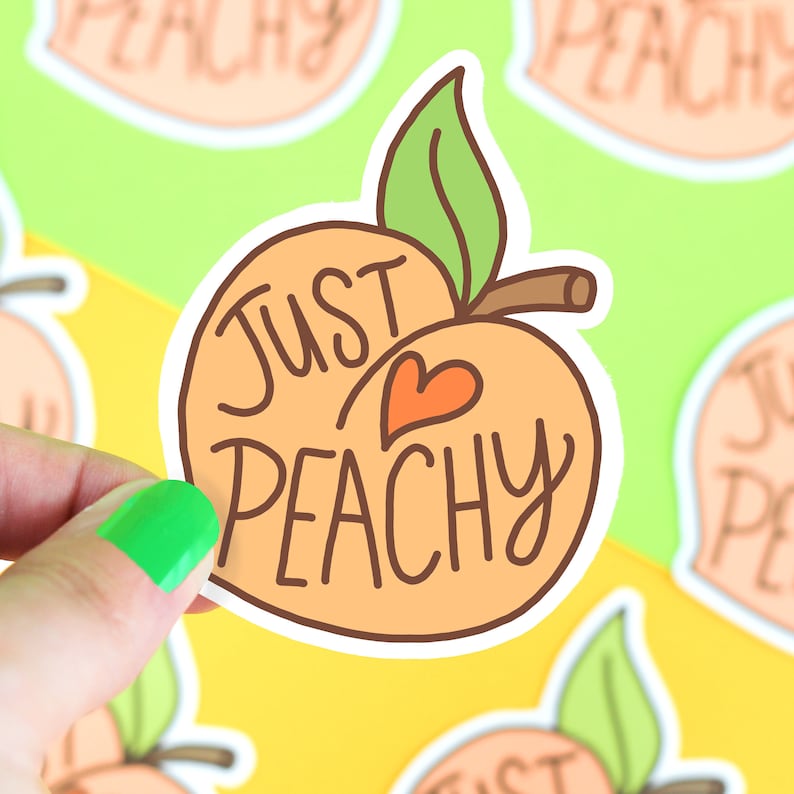 May include: A peach-shaped sticker with a white outline. The peach is orange with a red heart in the center. The text "Just Peachy" is written in brown cursive on the peach.