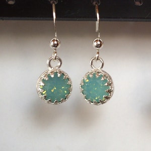 Könnte beinhalten: Ein Paar silberne Ohrhänger mit hellblauen Opal-Steinen, die in einem silbernen Filigranrahmen gefasst sind.