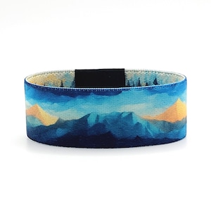 Puede incluir: Una pulsera tejida azul y amarilla con un diseño de paisaje de montaña.