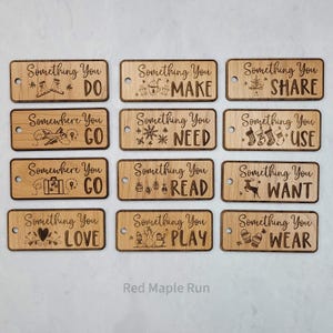 May include: Wooden gift tags with various engraved designs and text, including "Something You Do," "Something You Make," and "Something You Share." Each tag has a small hole for hanging. The text "Red Maple Run" is at the bottom.