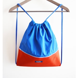 May include: A blue and orange drawstring backpack with a zippered pocket and the word "tmolu" on the front.