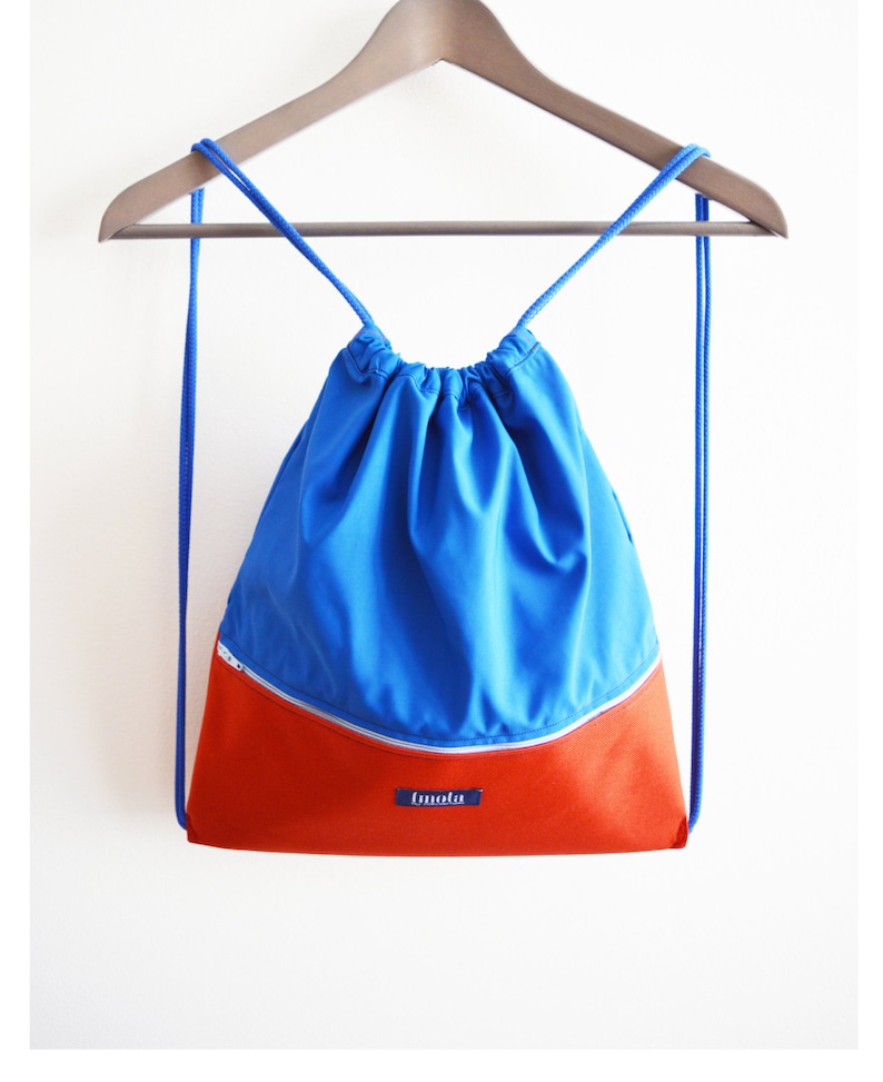 May include: A blue and orange drawstring backpack with a zippered pocket and the word "tmolu" on the front.
