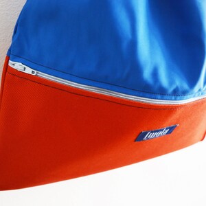 May include: A blue and red drawstring bag with a zippered pocket and a blue label that says "Lundle".