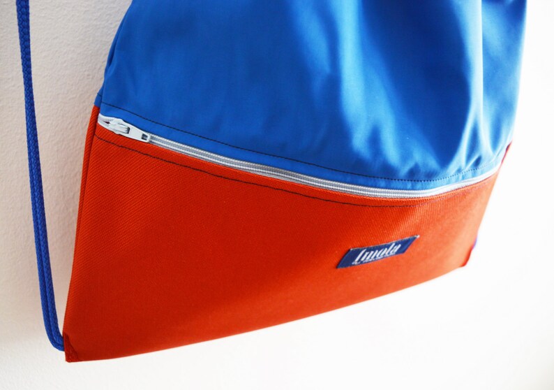 May include: A blue and red drawstring bag with a zippered pocket and a blue label that says "Lundle".