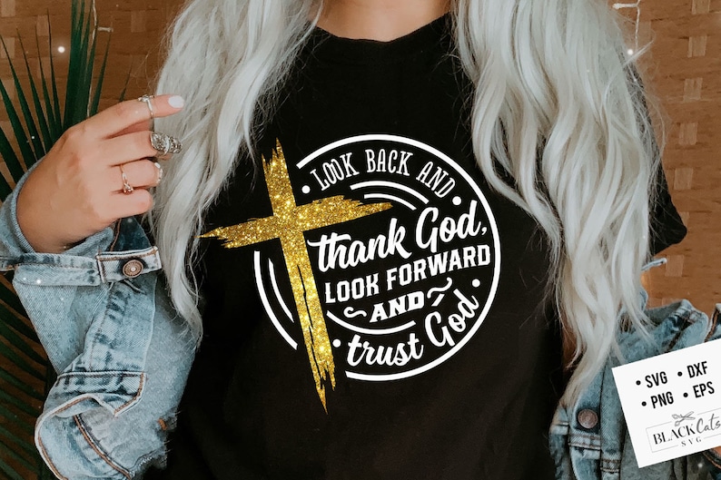 Może przedstawiać: Czarna koszulka z błyszczącym złotym krzyżem i napisem "Look Back and Thank God, Look Forward and Trust God" w białym okrągłym wzorze. Koszulka zawiera r&oacute;wnież ikony typ&oacute;w plik&oacute;w.