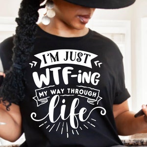 Könnte beinhalten: Ein schwarzes T-Shirt mit weißem Text, der "Ich bin gerade dabei, mein Leben zu WTF-en" lautet.