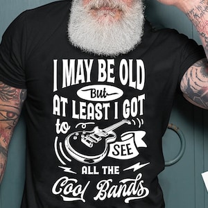 May include: A black t-shirt with white text that reads "I may be old but at least I got to see all the cool bands". The text is stylized with a guitar graphic and a lightning bolt.