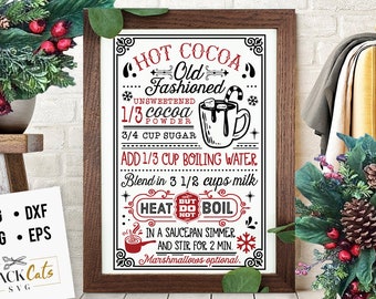 May include: A framed print with a hot cocoa recipe in black and red text. The recipe includes ingredients like cocoa powder, sugar, and milk. The frame is brown, and the print has decorative elements. A Black Cats SVG logo is in the lower left.