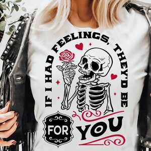May include: White t-shirt with a black and white graphic of a skeleton holding a rose. The text "If I had feelings, they'd be for you" is written in a circle around the skeleton.