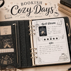 Pu&ograve; includere: Un'agenda a sei anelli nera con finiture dorate e tasche interne. La pagina aperta mostra un modello di recensione di libri con testo scritto a mano, tra cui il titolo The Moonlit Kingdom, una valutazione a cinque stelle e note. Include una penna nera.