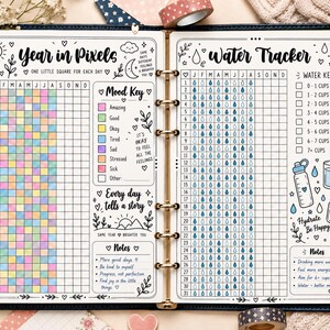 May include: A two-page planner spread featuring a Year in Pixels mood tracker with a color-coded key and a Water Tracker with a daily grid. The pages include hand-drawn illustrations of suns, moons, and water droplets, with text labels like Year in Pixels, Mood Key, Water Tracker, and Hydrate Be Happy.