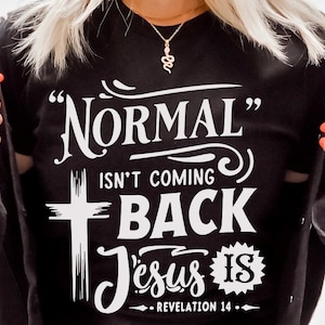 May include: Black t-shirt with white text that reads "Normal isn't coming back Jesus is - Revelation 14". The text is in a stylized font with a cross graphic.