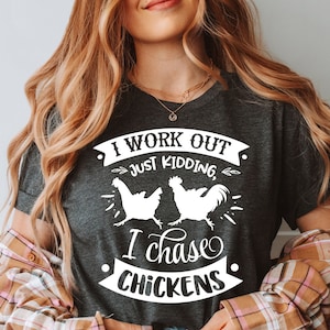 May include: A grey t-shirt with a white graphic that says "I work out just kidding, I chase chickens" with two white chickens running in opposite directions.