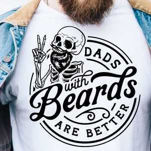 Puede incluir: Diseño gráfico en blanco y negro de un esqueleto con barba y señal de paz, con el texto "Dads with Beards are Better" en un círculo alrededor del esqueleto.